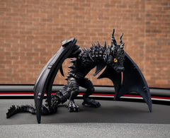 Dragon-like creature figurine with detailed scales and wings against a brick wall background